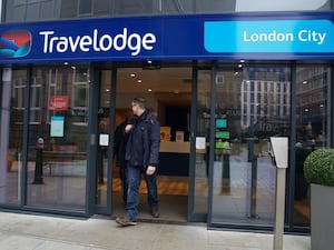 A person walking out the door of a Travelodge