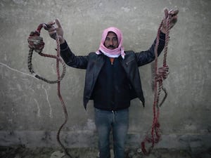 A man holding up two nooses in Saydnaya prison