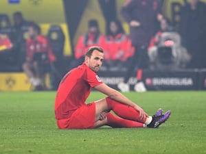 Bayern Munich striker Harry Kane sits on the turf at Borussia Dortmund's Signal Iduna Park after suffering an injury