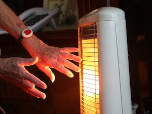 A pensioner's hands in front of an electric heater