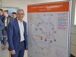 Mayor of London Sadiq Khan stands next to new Overground tube map