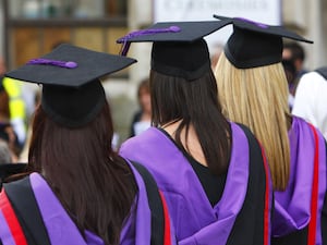 Three people in graduation caps and gowns seen from behind