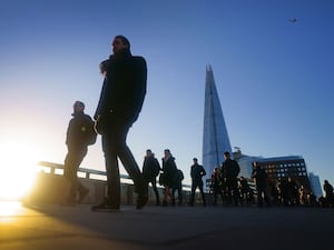 Commuters walking across London bridge at sunrise