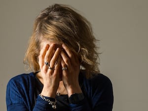 A woman holds her head in her hands