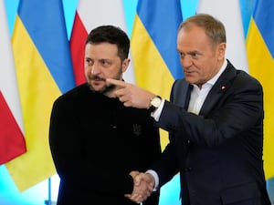 Donald Tusk points as he shakes hands with Volodymyr Zelensky