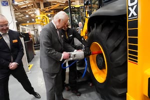 King Charles III fits a tyre to a backhoe loader during a visit to JCB World headquarters in Rocester. Photo: Arthur Edwards/The Sun/PA Wire