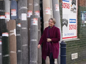 Home Secretary Yvette Cooper walks past rolls of carpet for sale in Bilston in the West Midlands