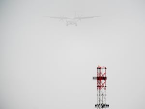 A plane lands in the mist at Cardiff Airport.