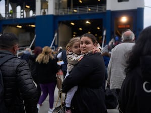 A woman with her child prepare to board a ferry bound for the Greek mainland, in the earthquake-struck island of Santorini, Greece