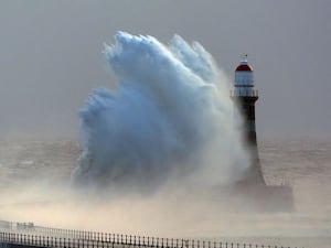 A big wave breaking over a lighthouse