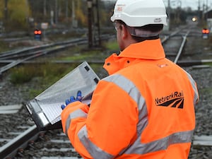 A Network Rail worker in an orange jacket and white hard hat