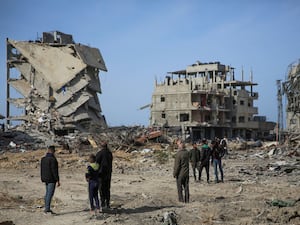 Palestinians stand near destroyed buildings