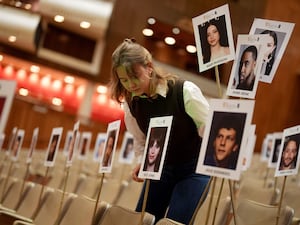 Pictures of heads on sticks are arranged on chairs