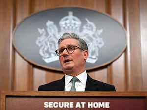 Sir Keir Starmer speaking in front of UK Government sign