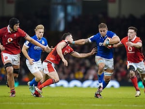 Italy player runs with the ball as a Wales player attempts to tackle