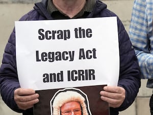 A person holds a piece of paper that reads ' Scrap the Legacy Act and ICRIR'