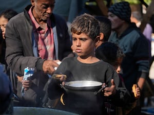 A Palestinian child queues for food in Deir al-Balah, in the Gaza Strip