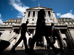 Silhouettes of people walking past the Bank of England