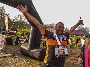 Michael Singh wearing a medal with his arms in the air in celebration