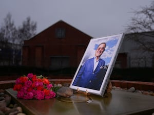 A photo of Vichai Srivaddhanaprabha with a floral tribute laid in front of it