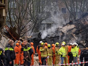 Fire and rescue crews stand in front of smoking debris