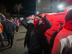 A man reacts in grief as the body of a child is brought to hospital following an air strike