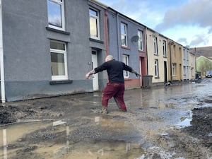 A Cwmtillery resident wades through mud and water after a mudslip in the area following Storm Bert