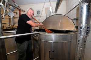 Dave Kelly works to stir the beer as it goes through the process