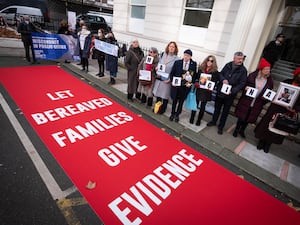 People stand by a red carpet demanding they be allowed to give evidence