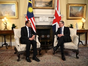 Malaysian Prime Minister Anwar Ibrahim and Sir Keir Starmer sitting in No 10 with their countries' flags behind them