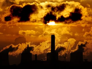 Sun casting orange light on silhouetted power plant