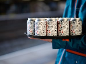 A train crew member holds a tray of beer cans