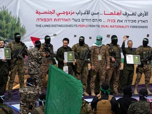 Israeli hostages, from left to right, Eliya Cohen, Omer Shem and Omer Wenkert on a stage with Hamas fighters