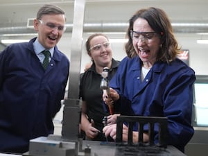 Liz Kendall wearing overalls and goggles while using a hammer alongside MP for Peterborough Andrew Pakes