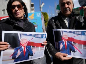 Palestinians carry defaced pictures of US President Donald Trump while protesting against his latest statements regarding the transfer of Palestinians from Gaza, in the West Bank city of Ramallah