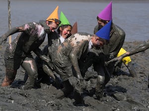 People wearing coloured cone-shaped hats messing around in mud