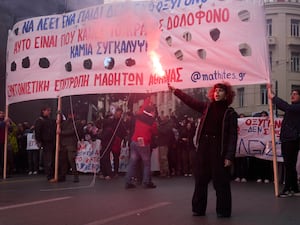 A student holds a flare during a protest in Greece