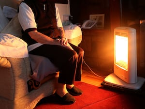 An elderly lady sitting at home with her electric fire on