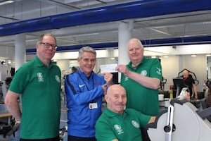 Robin Shields, left, and John Corser, right, present the cheque to Russell Tipson as Terry Astley demonstrates how the exercise machines are helping his rehabilitation

 