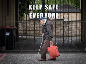 A pensioner walks past a sign that reads “Keep Safe Everyone” in Leith, Edinburgh