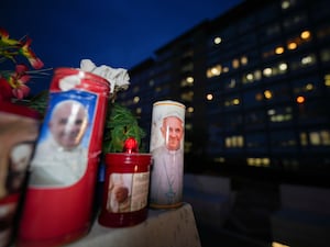 Candles with pictures of Pope Francis are laid under the statue of late Pope John Paul II outside Agostino Gemelli Polyclinic in Rome