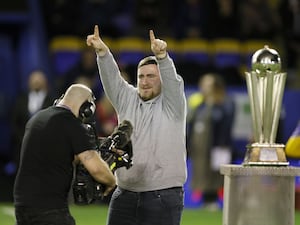 Luke Littler with his world championship trophy at Warrington's stadium