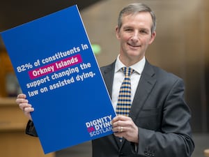 Liam McArthur holding a sign highlighting support for assisted dying