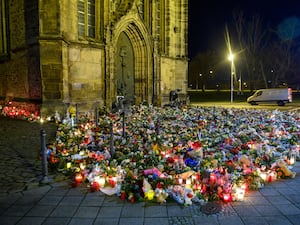 Flowers, candles, wreaths and stuffed animals lie in front of St John’s Church