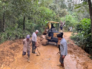 Workers clear a road cut off by a landslide following a flash flood in Pekalongan, Central Java, Indonesia