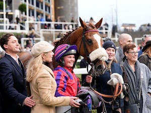 Racehorse surrounded by people including jockey