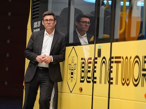 Andy Burnham leans on a yellow bus