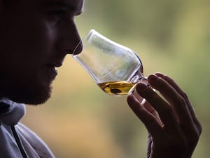 A man sniffs whisky in a glass