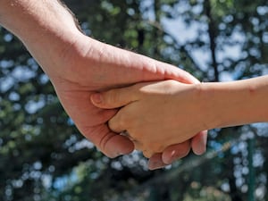 An adult and child holding hands