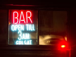 General view of a neon sign showing late opening hours at a bar in Soho, central London